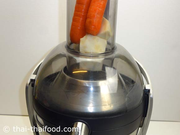 นำแครอทและหัวขึ้นฉ่ายใส่ในเครื่องแยกน้ำแยกกากผักและผลไม้